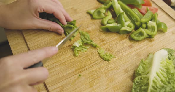 Green juicy salad is cut into small pieces on a wooden cutting board