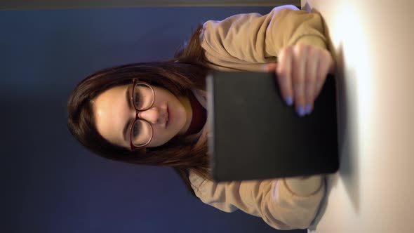 A Young Woman with a Tablet Sits at a Table. A Girl Is Sitting at Cafe at the Table with a Tablet