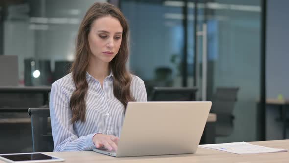 Young Businesswoman Thinking while using Laptop at Work