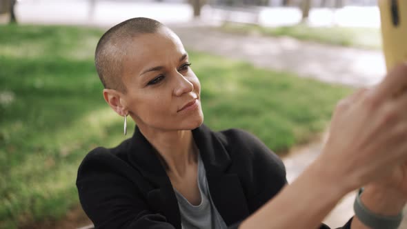 Pretty bald woman recording video by phone
