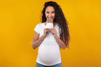 ocolate Bar Eating Junk Food Posing And Looking At Camera Isolated On Yellow Orange Studio Background. Guilty Pleasure And Binge Eating Habit
