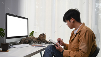 th digital tablet and cute cat lying in front of him.
