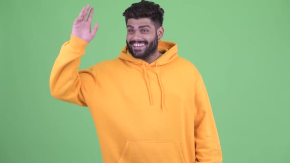 Happy Young Overweight Bearded Indian Man Waving Hand