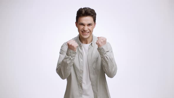 Young Guy Celebrating Achievement Shaking Fists and Folding Arms Posing to Camera Over White Studio