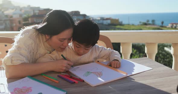 Asian mother doing homework with his little son outdoor on sunny day