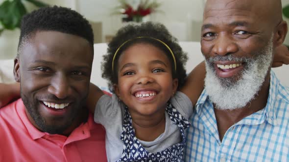 Portrait of happy african american grandfather with adult son and granddaughter