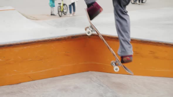 Skater Practicing in the Autumn Concrete Skate Park Making Tricks and Rides in Ramp