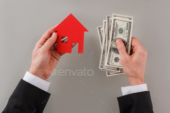 lar banknotes and red paper house. Buying and selling home. Real estate concept.
