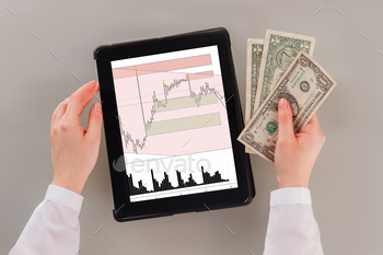 raphs. Young business woman hands holding money and pc tablet with stock exchange statistics.