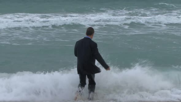 Male walking into ocean in suit