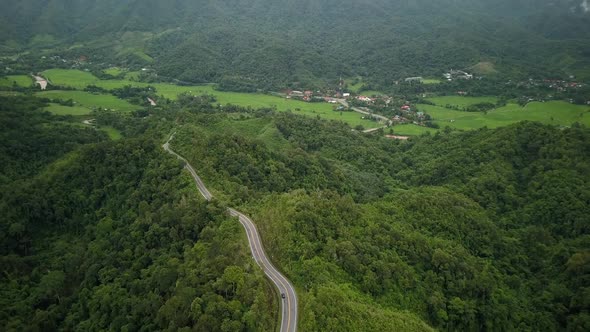 Aerial view flying above lush green tropical rain forest mountain with rain cloud cover during the r