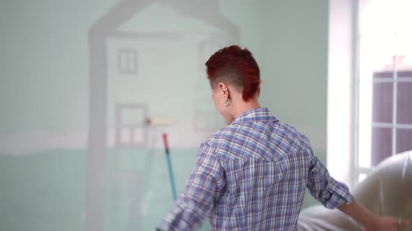 Back View Excited Satisfied Woman Gesturing Success Looking at House Drawing on Wall in Living Room