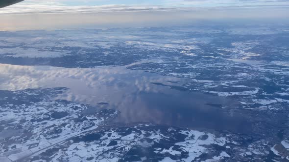 Flying over trondheim fjord with stunning reflection of the clouds on the water in a snow covered ar