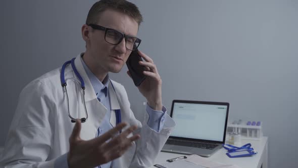 Smiling Doctor Having Phone Call at Desk