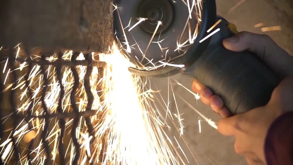 Closeup of worker using a grinder cuts metal in a workshop