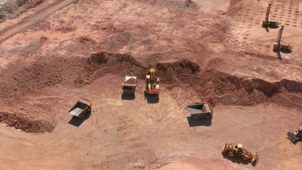 Aerial View of an Excavator Loading Red Stones Into Dump Truck in a Quarry, USA
