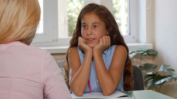 Adorable Happy Young Girl Talking To Her Teacher at Class