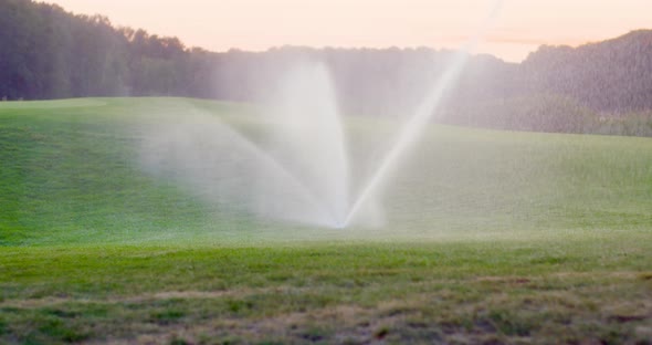 Medium Shot of Grass Sprinkler Splashes Water Over the Lawn