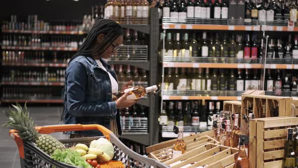 Young Lady Choosing a Bottle of Wine in a Supermarket