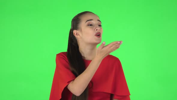 Portrait of Pretty Young Woman Is Smiling and Showing Blowing Kisses. Green Screen