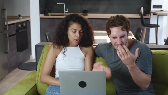 Couple Quarreling While Using Laptop While Sitting on Sofa at Home. Family Conflict