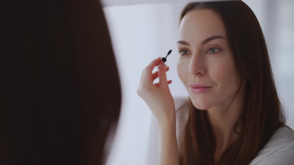 Woman Painting Eyebrows Near Mirror