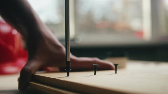 Woman Builder Tightening Screws with Manual Screwdriver Into Wooden Board Closeup