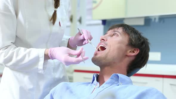 Close up of attractive man having dental examination of aching tooth