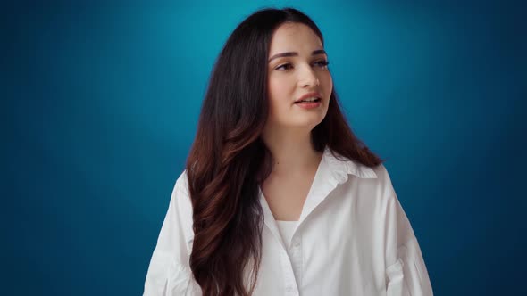 Stressed Young Woman Tries to Calm Down Breathing Deeply Against Blue Background