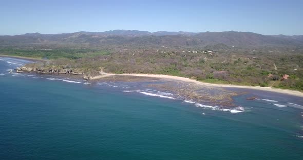 Aerial drone view of the beach, rocks and tide pools in Playa Palada, Guiones, Nosara, Costa Rica.