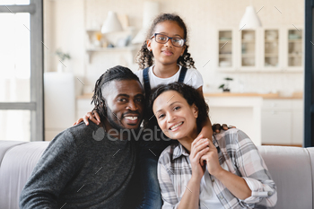 of three, parents and preteen daughter hugging embracing together relaxing on the couch at home. Homeowners, mortgage loan, real estate