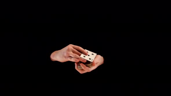 Magician Makes Trick with Playing Cards on Black Background