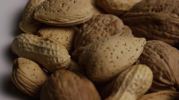 Cinematic, rotating shot of a variety of nuts on a white surface