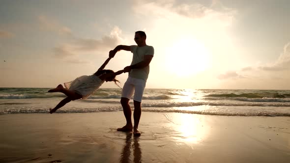 Happy Father and Daughter Playing on the Beach at Sunset