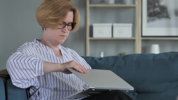 Old Senior Woman Leaving Couch after Completing Work on Laptop