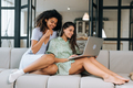Two beautiful young women relaxing on the living room floor looking at a laptop - PhotoDune Item for Sale