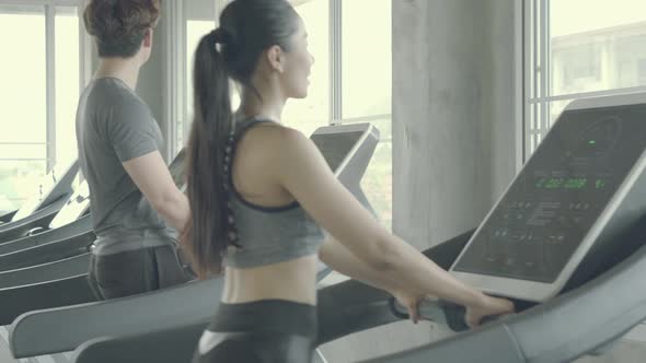 Asian young man and woman doing cardio exercise training with running on treadmill in sport gym.