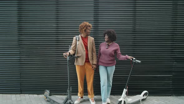 Portrait of Cheerful Afro Friends with E-Scooters on Street