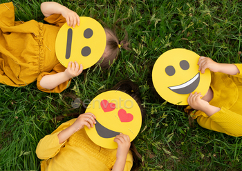 board emoticons with different emotions in their hands: a sad, smiling happy smile, a loving smile with hearts instead of eyes. World Emoji Day