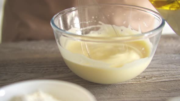 Pouring Sunflower Oil Into Beaten Egg Yolks For Baking In The Kitchen.