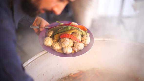 Chef Takes Out the Heads of Garlic and Pepper From the Cauldron with Uzbek Pilaf