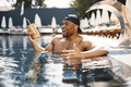 Portrait of a black american man standing in a swimming pool with cocktails - PhotoDune Item for Sale