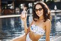 Portrait of a young girl in a swimwear sitting near pool and holding cocktail - PhotoDune Item for Sale