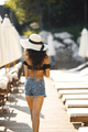 Back side portrait of a young girl with a cocktail in a swimwear standing near sunbeds - PhotoDune Item for Sale
