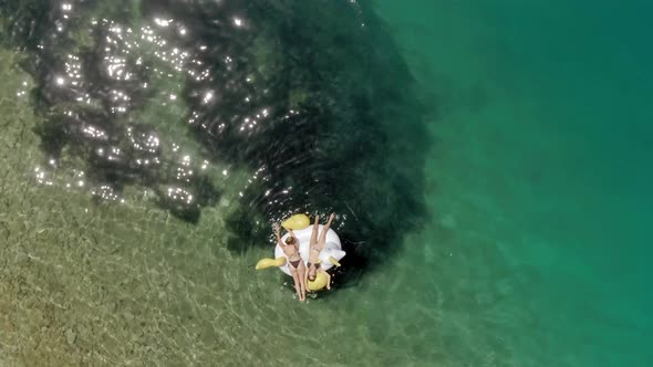 Aerial view of two women floating on inflatable in Panagopoula, Greece.