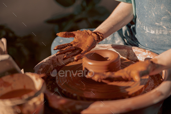 Female master shaping clay on pottery wheel in atelier