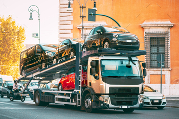 City Street. Auto Transport Broker Or Car Transporter. Auto-transport Carrying New Fiat Cars In City Street. Auto Transport Broker Or Car Transporter