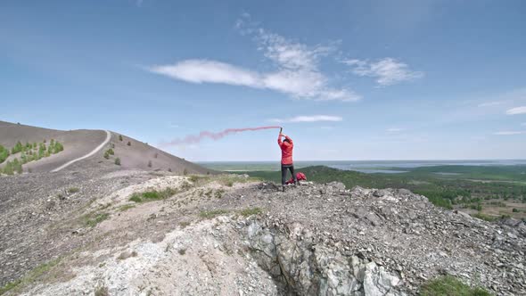 Rear View of Hiker in Mountains with Smoke Grenade