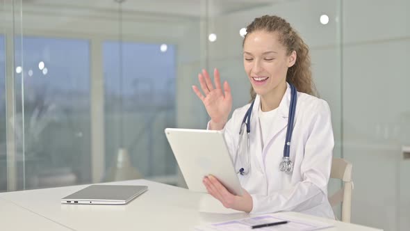 Young Female Doctor Doing Video Chat on Tablet in Office