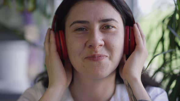 Headshot Portrait of Caucasian Relaxed Woman Listening to Music in Headphones Smiling Looking at